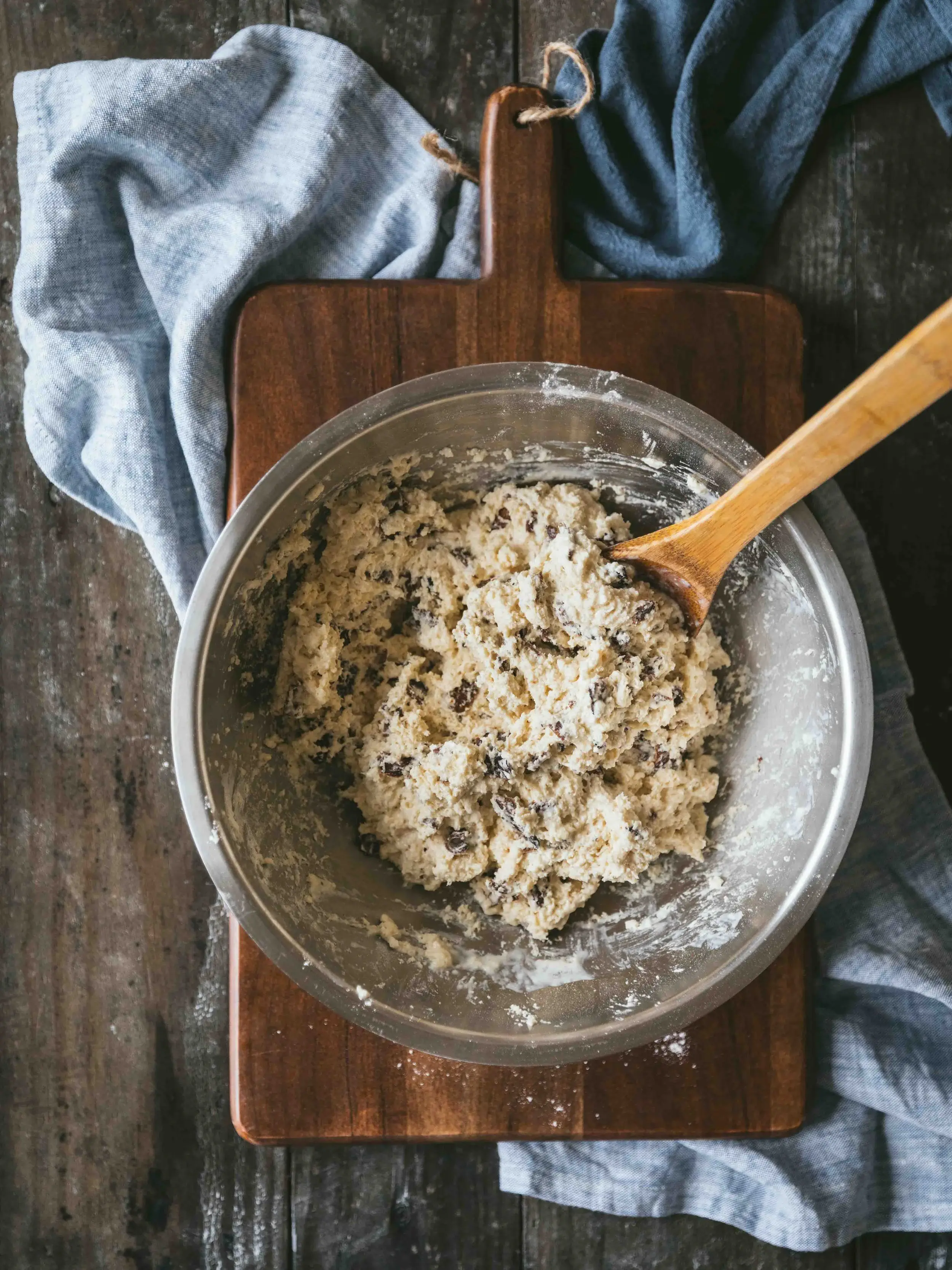 Top-down shot of MyBacon Biscuit Dough in a silver pan on a dark cutting board with a wooden spoon in the bowl for mixing