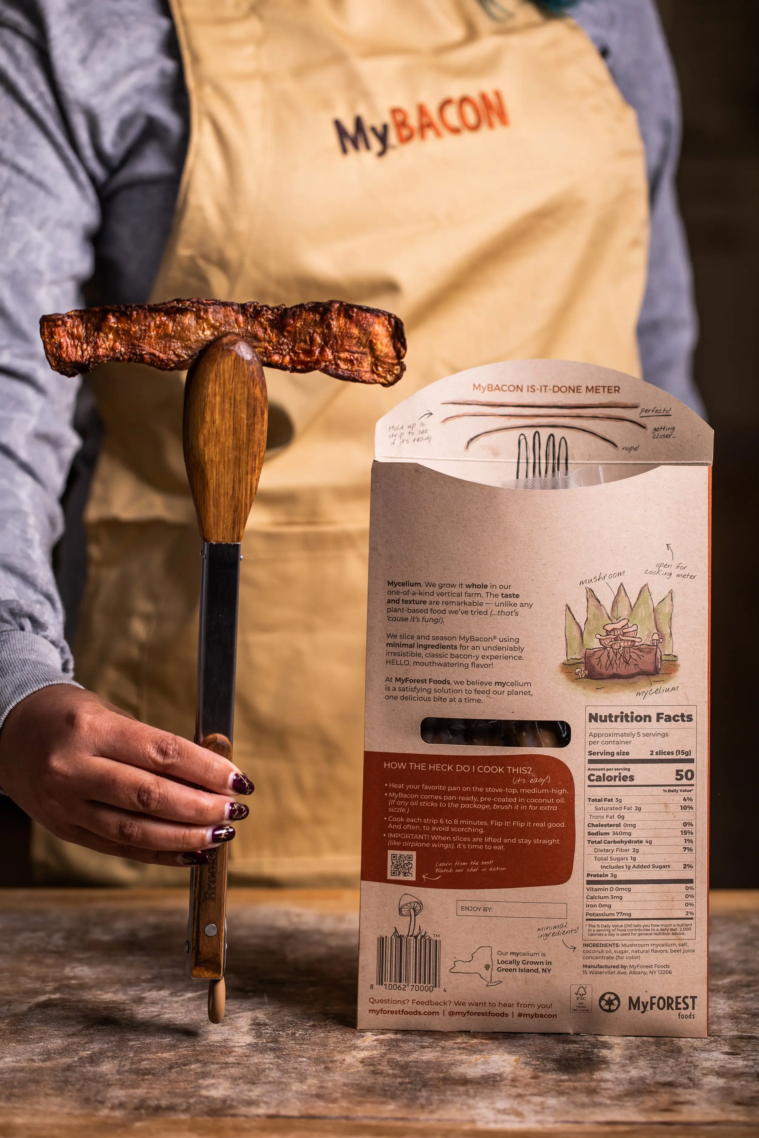 Picture of MyBacon slice being held by tongs, planking stright as if ready to eat