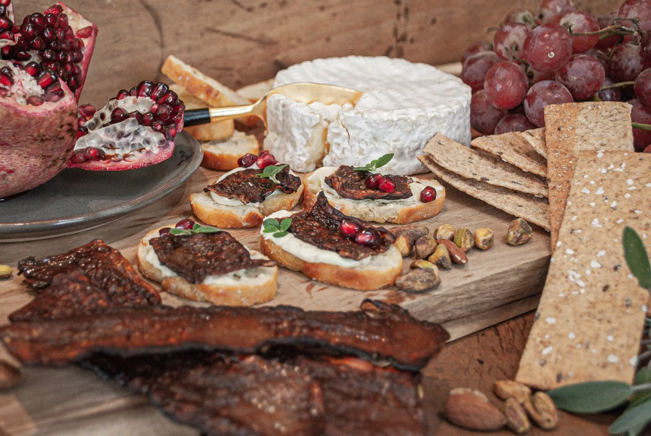 Charcuterie spread including fancy cheeses, crackers, fruit, nuts and strips of MyBacon