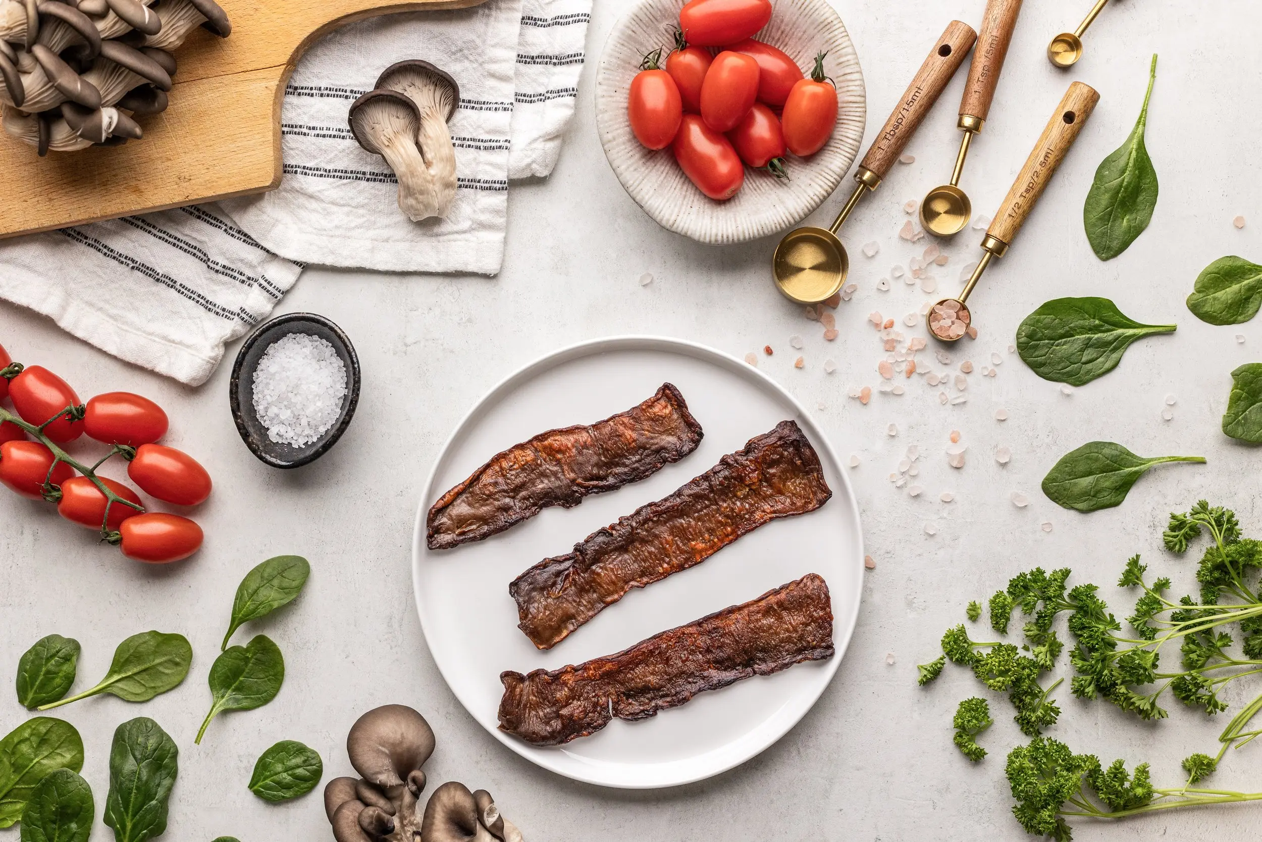 Cooked MyBacon strips on a plate with vegetables and oyster mushrooms