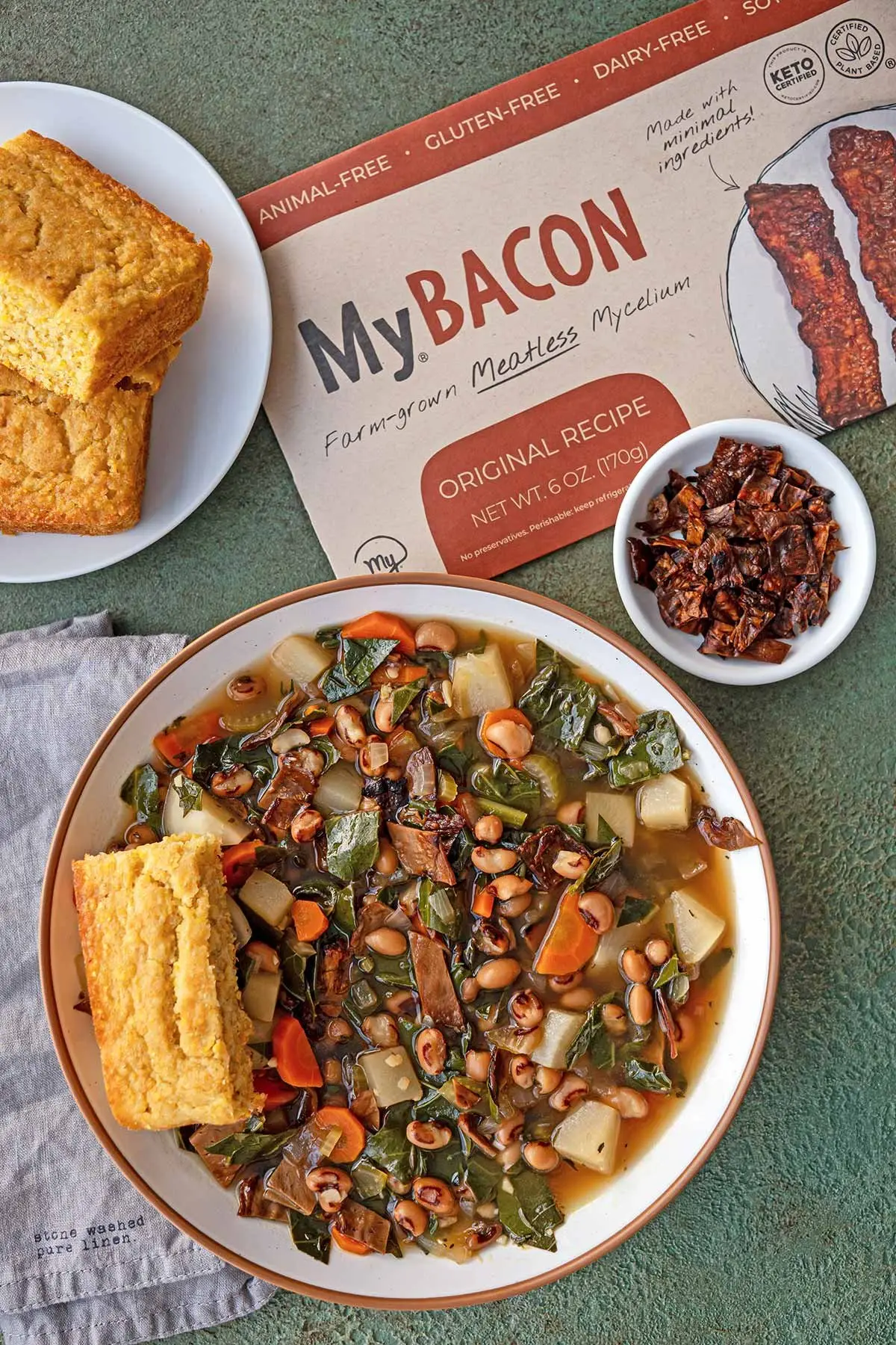 Top-Down Photo of Black-Eyed Pea & MyBacon Soup in a bowl with cornbread, MyBacon bits and a package of MyBacon